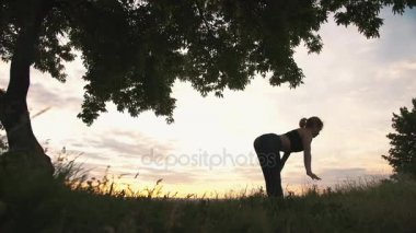 Güzel güneş doğarken pratik yoga bir kadın silüeti