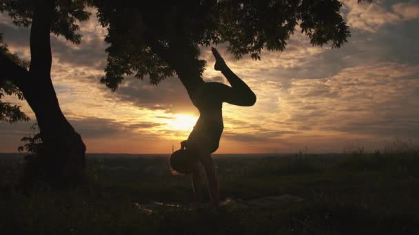 Silueta de una mujer practicando yoga al amanecer — Vídeo de stock