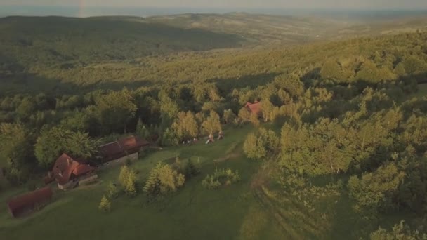 Flygfoto flyger. Dalar och kullar täckta med gröna träd och regnbåge över dem. — Stockvideo