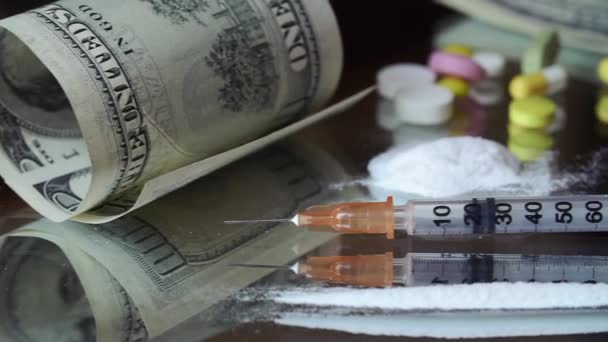Pigułki, dolarów, jednorazowe strzykawki i kokainy na stół szkło — Wideo stockowe