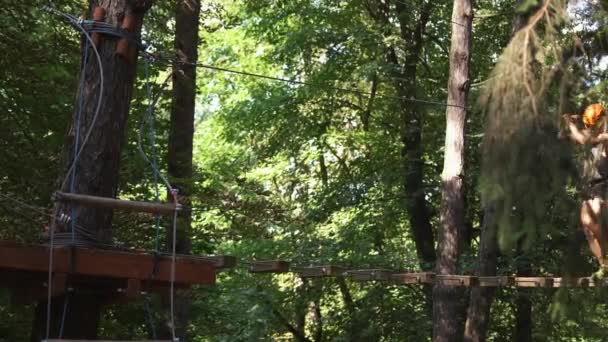 Чоловік ходить на висячій доріжці в мотузковому парку — стокове відео