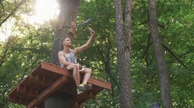 Adam bir selfie ağaç bir ip parkta oturup telefonunu alır