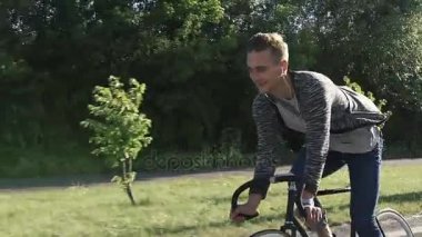 Genç adam cadde boyunca bir bisiklet ile gidiyor