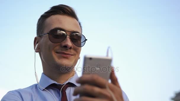 Young man checks his phone standing on the street — Stock Video