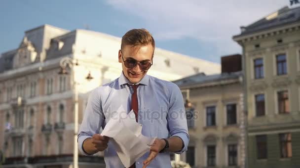 Mladý muž kontroluje jeho papíry, stojící na ulici — Stock video