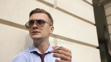 Genç adam sokakta bekleyen bir puro içiyor