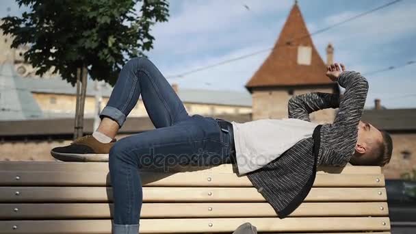 Tired young man lies on the bench — Stock Video