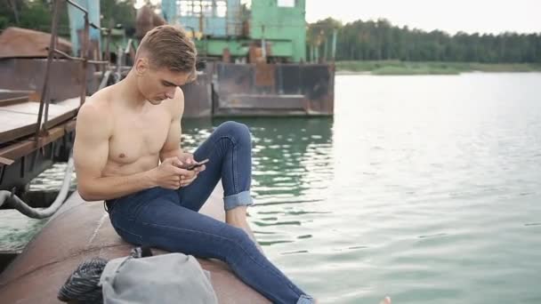 Man sits on the bay with his phone — Stock Video