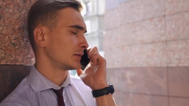 Jonge man controleert zijn draagkracht van de telefoon op straat — Stockvideo