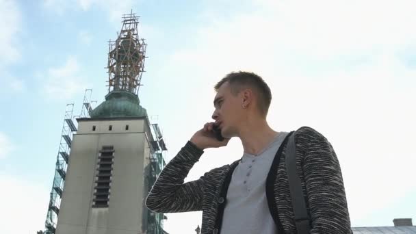 Молодий чоловік говорить по телефону, що стоїть на вулиці — стокове відео