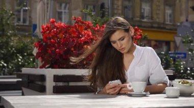 O kırmızı çiçekler önce restoranda otururken esmer Bayan bir şey onun telefonunda yazıyor