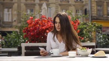 O kırmızı çiçekler önce restoranda otururken esmer Bayan bir şey onun telefonunda okur