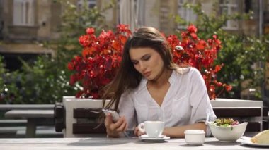 O kırmızı çiçekler önce restoranda otururken esmer Bayan bir şey onun telefonunda okur