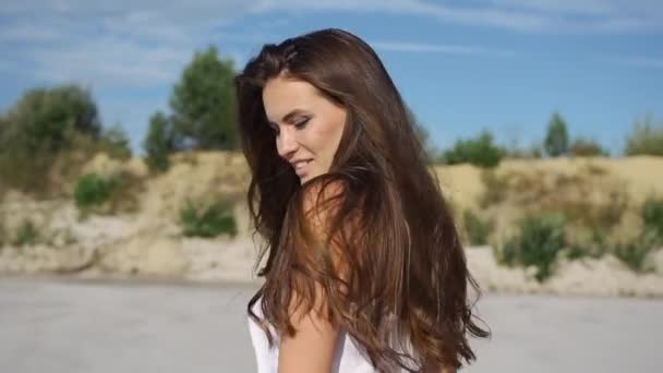 Vrouw met lange haren heeft plezier dansen op het zand onder de blauwe hemel — Stockvideo