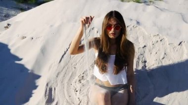 Beyaz üst ve kırmızı güneş gözlüğü baştan çıkarıcı esmer kadın kum Rüzgar üzerinde çalış