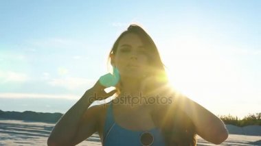 Zarif bir kadın kum Yüzme elbiseli poz arkasından güneş parlıyor