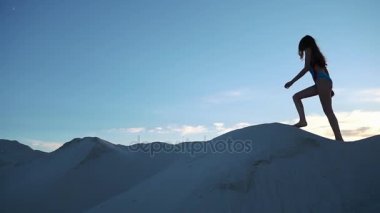 Mavi Yüzme elbiseli kadın kumul üzerinde akşam yürür.