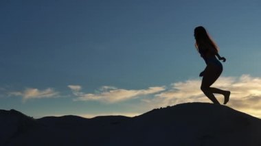 Mavi Yüzme elbiseli kadın kumul üzerinde akşam yürür.