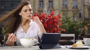 Esmer Bayan salata yiyor ve o kırmızı çiçekler önce restoranda otururken bir şey onun tablet üzerinde saatler