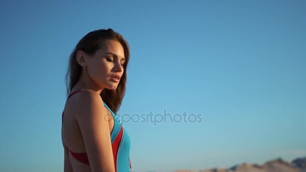 Brunette meisje met lang haar vormt in blauwe zwemmen pak op witte zand — Stockvideo