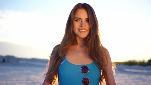 Lenyűgöző barna nő, hosszú haj táncok az esti fények a strandon — Stock videók