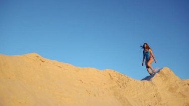 Mavi Yüzme elbiseli kadın kumul üzerinde akşam yürür.