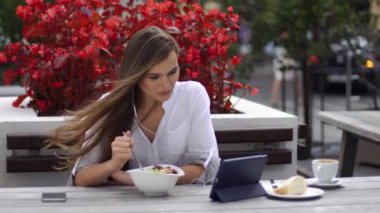 Esmer Bayan salata yiyor ve o kırmızı çiçekler önce restoranda otururken bir şey onun tablet üzerinde saatler