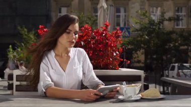 O kırmızı çiçekler önce restoranda otururken esmer Bayan tablet ile çalışır