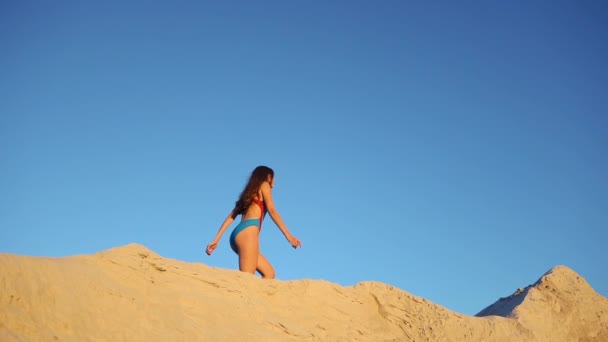 Wanita berbaju renang biru berjalan di bukit pasir di malam hari — Stok Video