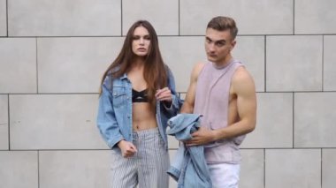 Erkek ve kadın gri bir duvar önce rahat sokak tarzı poz giyinmiş