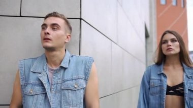 Uzun saçlı çarpıcı kadın önce gri bir duvar poz kot ceketli adamı arkasında duruyor