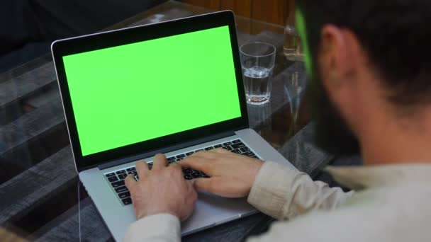 Человек работает на ноутбуке с зеленым экраном — стоковое видео