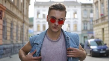 Kırmızı güneş gözlüklü adam onun kot yelek alır ve cadde boyunca yürüyüş onun omzuna koyar