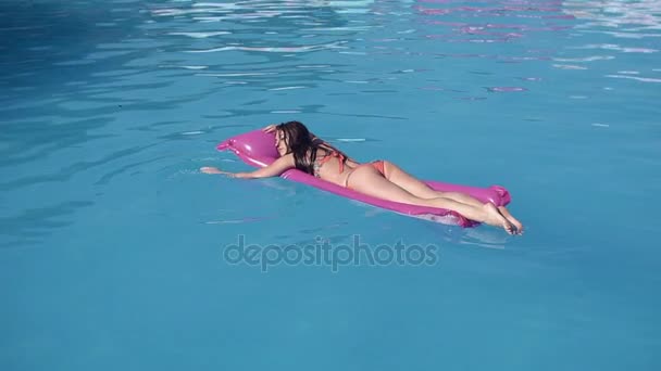 Hermosa mujer joven que se relaja en la piscina en verano, tumbado en el salón inflable. Hora de verano — Vídeo de stock