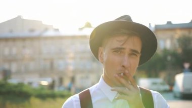 Sunset bulvarında cadde boyunca yürür iken siyah şapkalı genç adam sigara içiyor