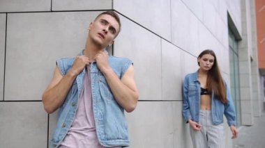 Uzun saçlı çarpıcı kadın önce gri bir duvar poz kot ceketli adamı arkasında duruyor