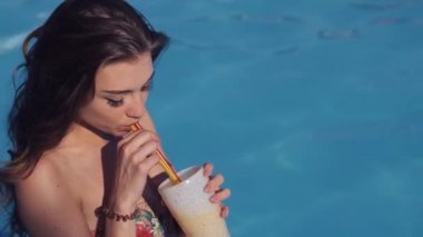 Yakın kadar güzel havuz kenarında oturan ve bir kokteyl içme genç kadın