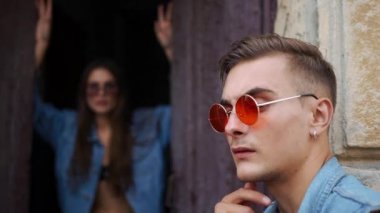 Erkek ve kadın ile güneş gözlüğü poz daha önce eski bir kapının sokakta rahat sokak tarzı giyinmiş