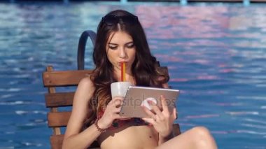 Bir tablet ve Relax havuzu kullanan güzel kız. Bir kokteyl içiyor