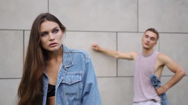 Menino vestido com camisa rosa fica atrás de uma mulher sedutora em jaqueta de jeans — Vídeo de Stock