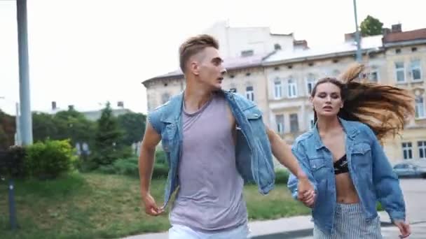 Man och kvinna klädd i casual street stil köra på gatan — Stockvideo