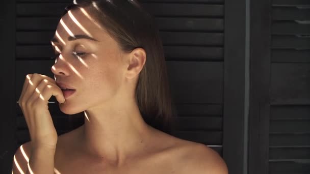 Zonnestralen liggen op dames gezicht terwijl ze haar lippen zacht en verleidelijk raakt — Stockvideo