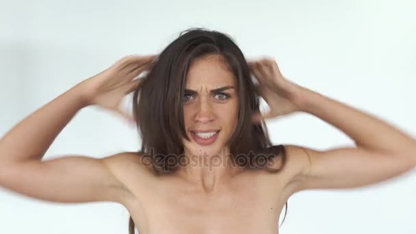 Злая молодая женщина трясет волосами и кричит стоя на белом фоне — стоковое видео