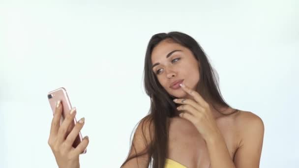 Приголомшлива молода жінка з довгим волоссям і веснянками трясе волосся, приймаючи селфі на свій смартфон — стокове відео
