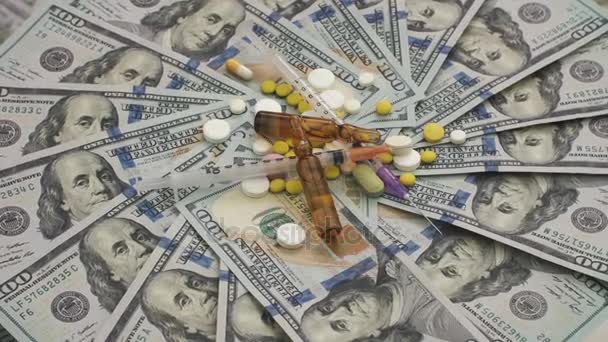 Pills, ampoules and syringes rotating on money - healthcare cost concept — Stockvideo