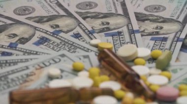 Hap ve para - sağlık maliyet kavramı dönen ampul. Yakın çekim. Kamera odaklama dolardır