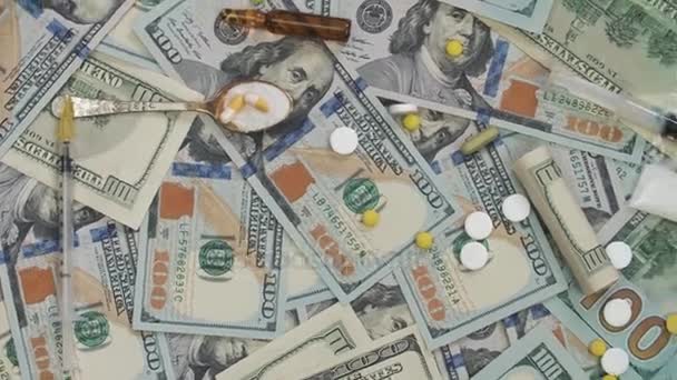 Comprimidos, drogas, cocaína, seringa em notas de dólar. O quadro gira no sentido anti-horário . — Vídeo de Stock