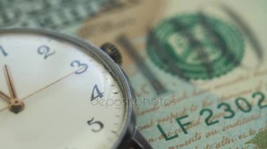 Eski saati onde masaya yüz dolarlık banknot yatıyor