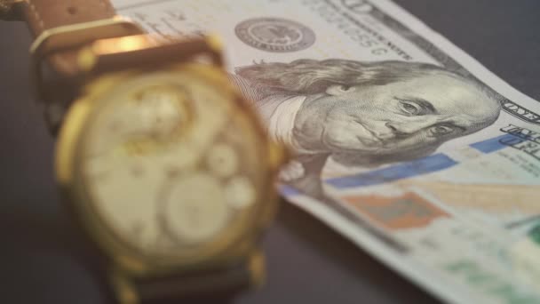 Gros plan sur le lecteur d'horloge dans une montre chic qui repose sur un billet de cent dollars — Video