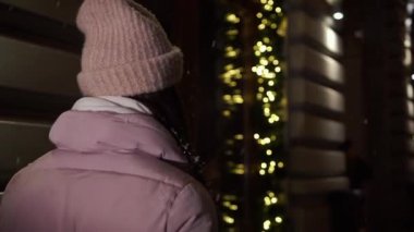 Vitrinler, yakınındaki sokakta yürürken güzel çekici kız çelenk, onun elinde kahvesiyle ile dekore edilmiş. Yeni yıl Noel. Akşam çekim